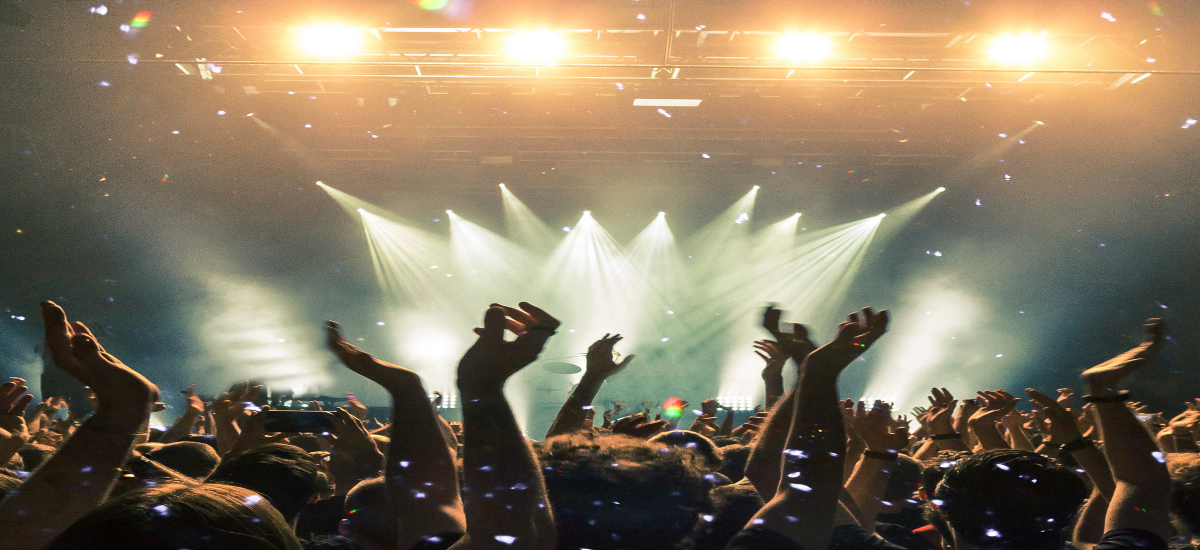 Crowd enjoying a live performance at a music venue with bright stage lights and confetti.