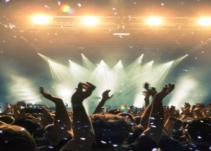 Crowd enjoying a live performance at a music venue with bright stage lights and confetti.